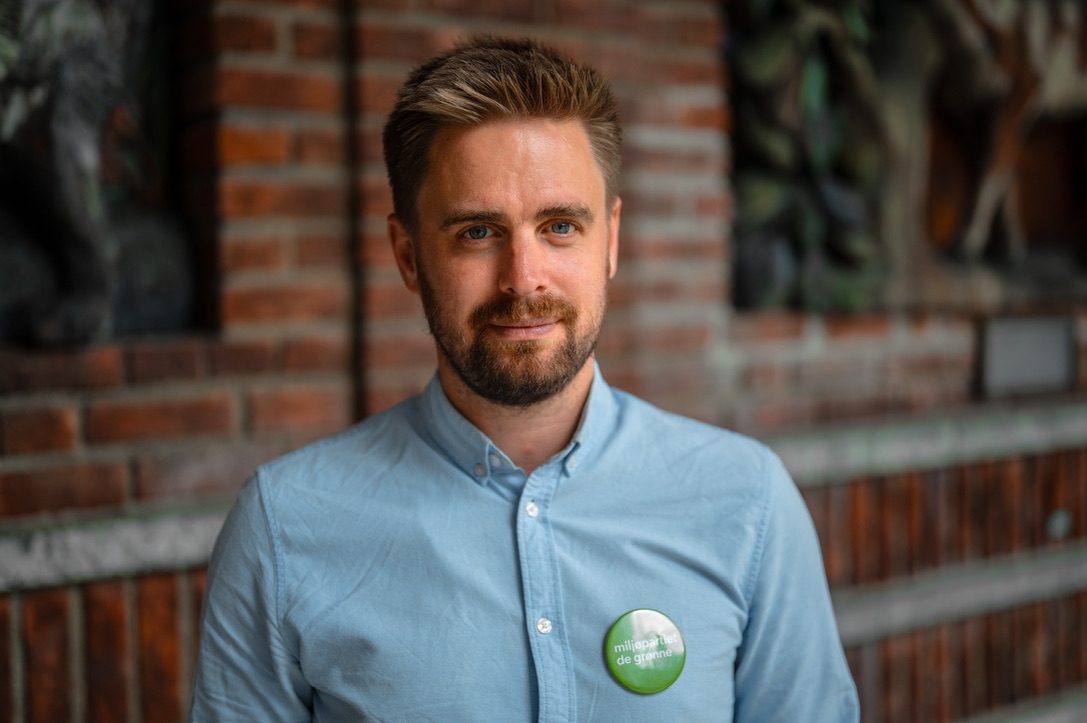 Eivind Trædal foran en murvegg, med MDG-button på skjorta